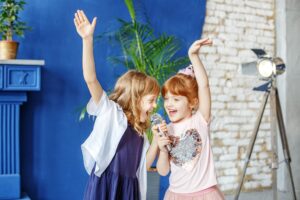 Two little funny children dance and sing a song in karaoke. The